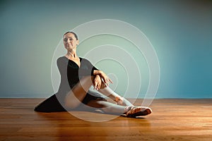 Adult beautiful woman 45-55 years old, ballerina in pointe shoes sits on the floor and poses for the camera. Active old