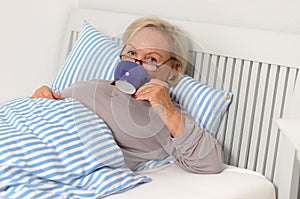 Adult Blond Woman on her Bed Holding her Cup