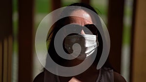 Adult brunette woman with sunglasses and medical face mask outdoors