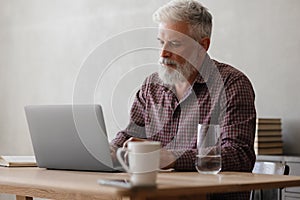 adult business man with gray hair is working at a laptop in his office. career finance and marketing, senior executive