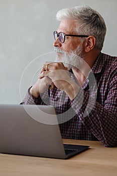 adult business man with gray hair is working at a laptop in his office. career finance and marketing, senior executive