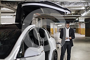 Adult in business suit thumbing through cash in EV parking