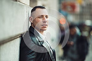 Adult businessman looking to the side and waiting for somebody in big city photo