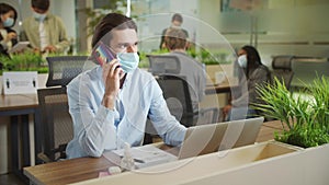 An adult businessman is talking with someone on the phone during working