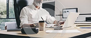 Adult businessman working at modern coworking office.Confident man using contemporary mobile laptop.Wide.