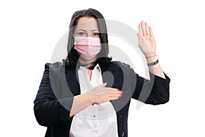 Adult businesswoman wearing pink mask making oath gesture