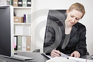 Adult Businesswoman Writing on Top of her Desk