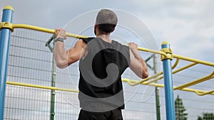 Adult caucasian athlete is doing the ejection pull exercise on a crossbar at the gym at the park