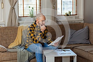 Adult caucasian bald man watching document for purchase or leasing real estate. Concept of loan and mortgage