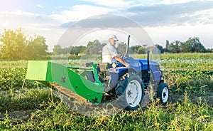 A adult caucasian farmer driver on a farm tractor drives to the field to harvest potatoes. Agro industrial technologies. Growing