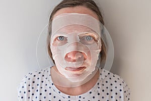 Adult caucasian female using hydrating sheet face mask with hyaluron
