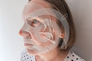 Adult caucasian female using hydrating sheet face mask with hyaluron photo