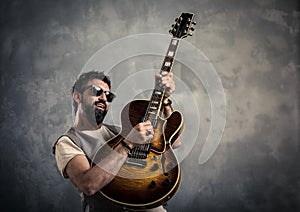 Adult caucasian guitarist portrait playing electric guitar on grunge background. Music singer modern concept