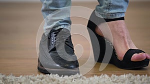 Adult Caucasian intersex person standing in one men`s broggi boot and one women`s high heel shoe. Extreme close-up of