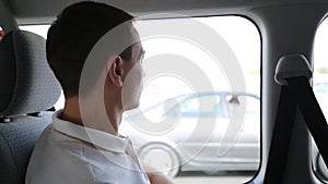 An adult caucasian male of 35-40 years old is looking out the window while riding in a car.