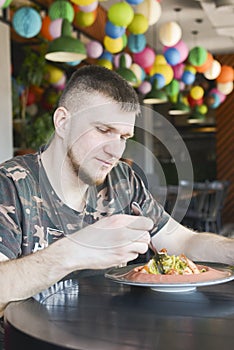 Adult caucasian man at a restaurant eating spinach pasta with shrimps. Traditional Italian cuisine, eating out concept