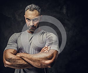 Adult caucasian muscular bodybuilder showing his muscles with arms crossed and looking on camera, portrait look