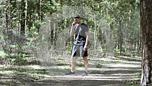 Adult caucasian strong athlete is having a phoen talk on his smartphone while standing on a track at the park