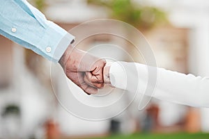 Adult, child and hands in fist bump for trust, agreement or partnership in generations against a blurred background. Big