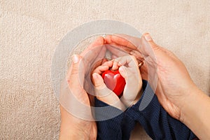 Adult and child hands holding red heart