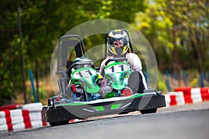 Adult and child in helmets driving karting on track