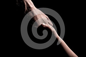 Adult and child holding hands on black background adult hand supporting child