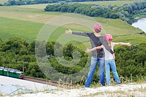 Adult and child standing on a mountaintop near river.