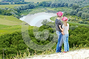 Adult and child standing on a mountaintop near river.