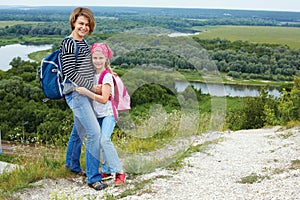 Adult and child standing on a mountaintop near river.
