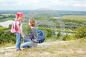 Adult and child standing on a mountaintop near river.