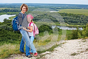 Adult and child standing on a mountaintop near river. Mother w