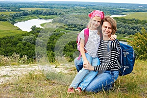 Adult and child standing on a mountaintop near river. Mother w