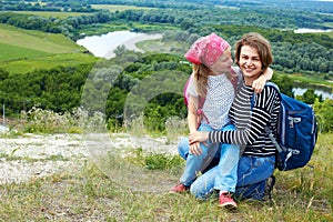 Adult and child standing on a mountaintop near river. Mother w