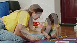 Adult and child working together on a puzzle game on a colorful mat. Collaborative learning and problem-solving concept