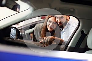 Adult couple choosing new car in showroom