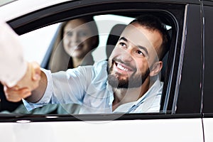 Adult couple choosing new car in showroom