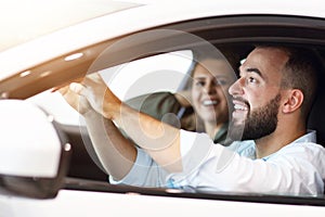 Adult couple choosing new car in showroom