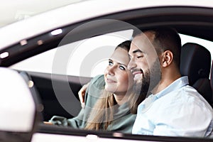 Adult couple choosing new car in showroom