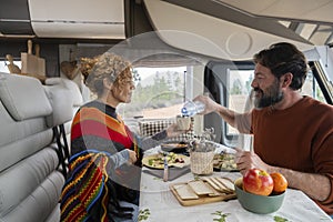 Adult couple enjoy time eating inside camper van in mountain holiday free vacation together. Man and woman in vanlife or tourist