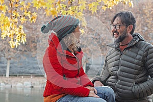 Adult couple enjoy together outdoor leisure activity in weekend travel vacation talking on a lake rive coast. Autumn season and