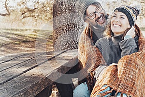 Adult couple have fun together with love and laughing sitting together on a bench in autumn season park. People enjoy outdoor