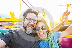 Adult couple have fun together on a roller coaster in amusement park taking selfie picture with the phone. People enjoying holiday