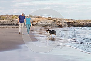 Adult couple in love walk outdooor holding hands and enjoying their nice beautful pet dog at the beach - concept of end lockdown photo