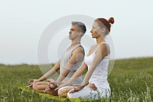 Adult couple meditating in summer spring countryside