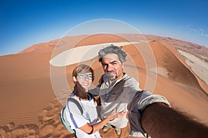 Adult couple taking selfie on sand dunes at Sossusvlei in the Namib desert, Namib Naukluft National Park, main travel destination