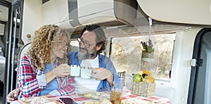 Adult couple toasting inside camper van during travel adventure life vacation. Motor home camper vehicle indoor leisure activity.