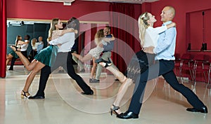 Adult couples dancing active dance together in modern studio