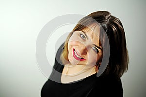 Adult curvaceous beautiful woman looks into the frame Close up face Black dress and red lipstick She has brown hair A