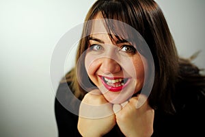 Adult curvaceous beautiful woman looks into the frame Close up face Black dress and red lipstick She has brown hair A