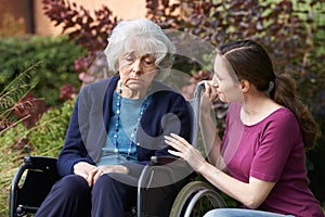 Adult Daughter Comforting Senior Mother In Wheelchair